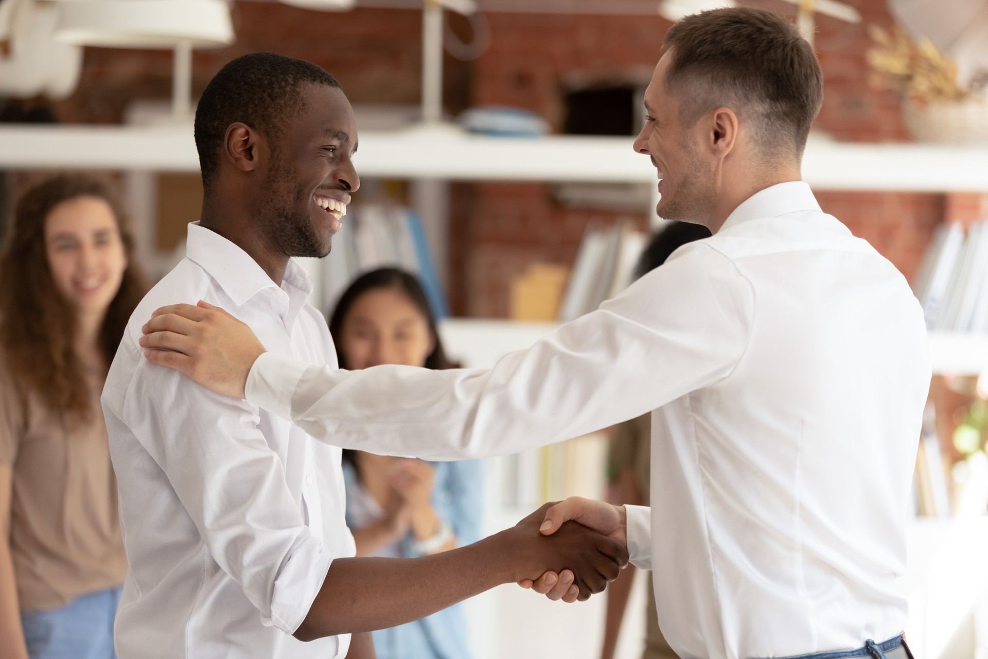 Caucasian executive handshaking promoting successful happy african worker expressing gratitude